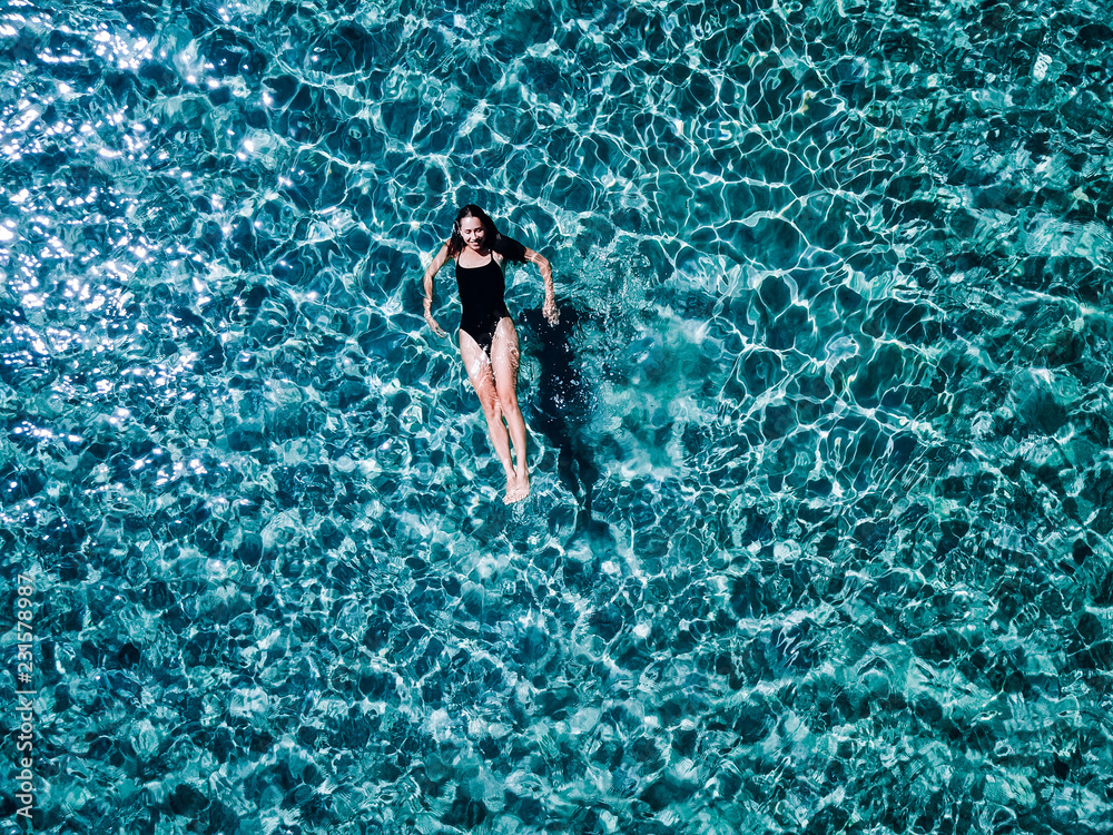 Young girl in a black swimsuit swims in the sea.