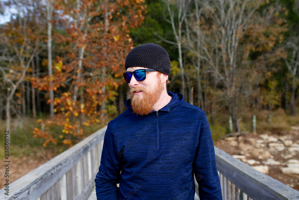 Redheaded man standing on bridge over lake