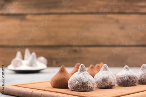 Chocolate truffles covered with powdered sugar and cocoa powder, wooden background, copy space.