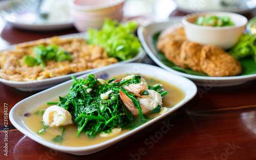 Stir-fried Vegetable fern with shrimp in white dish on wooden table photo