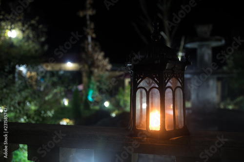 Retro style lantern at night. Beautiful colorful illuminated lamp at the balcony in the garden. Selective focus © zef art
