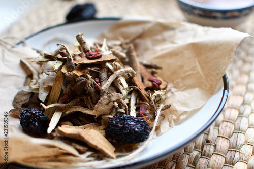 Chinese traditional medicine script. Herbal tea with jujubes, goji berries, gingseng roots and others on parchment paper on neutral background. photo