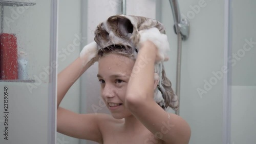 Vídeo do Stock: Smiling young girl bathing under a shower at home. Beautiful teen girl taking shower and washing in the bathroom. Happy child washing head, face and body with water. | Adobe Stock 