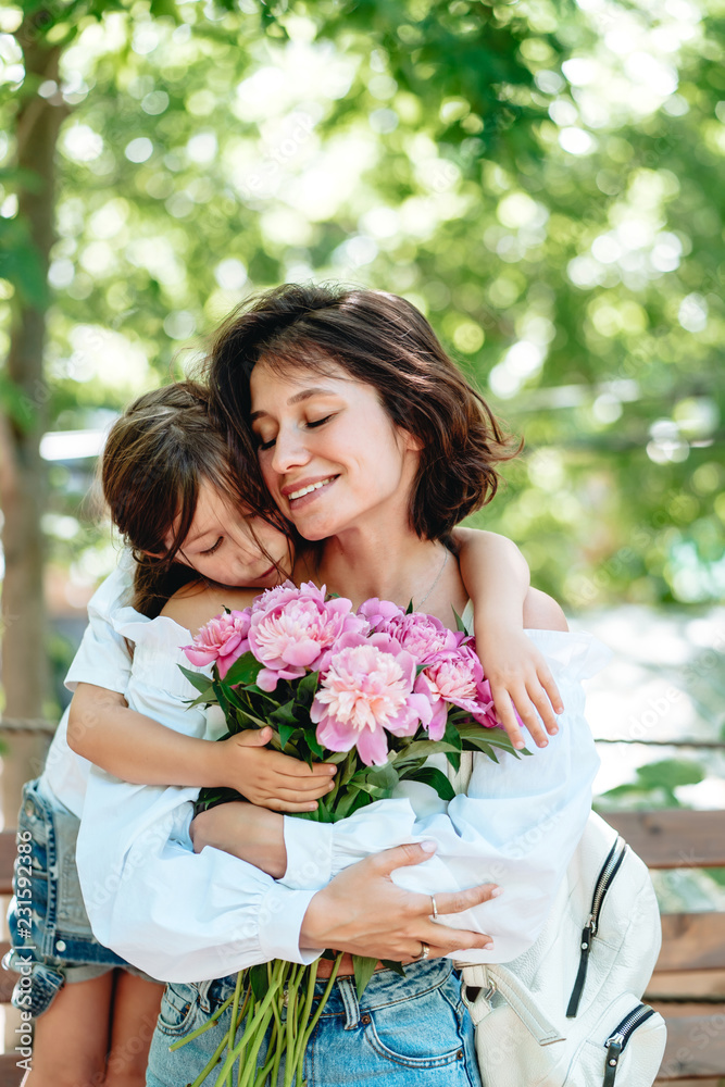 Young mother with a bouquet of flowers is having fun with her daughter Young mother with a bouquet of flowers is having fun with her daughter