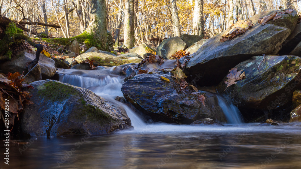 Water runs down a creek in Shenandoah National Park as signs of fall appear with leaves on the ground and colors in the trees Water runs down a creek in Shenandoah National Park as signs of fall appear with leaves on the ground and colors in the trees