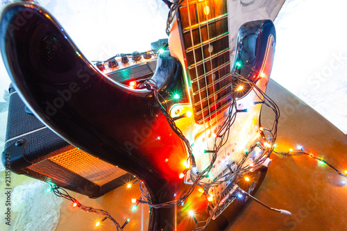 electric guitar and amplifier in bright colors of festive lights of the garland