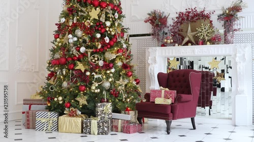 New year green tree decorated with presents and flashing garland, classic white christmas interior background.