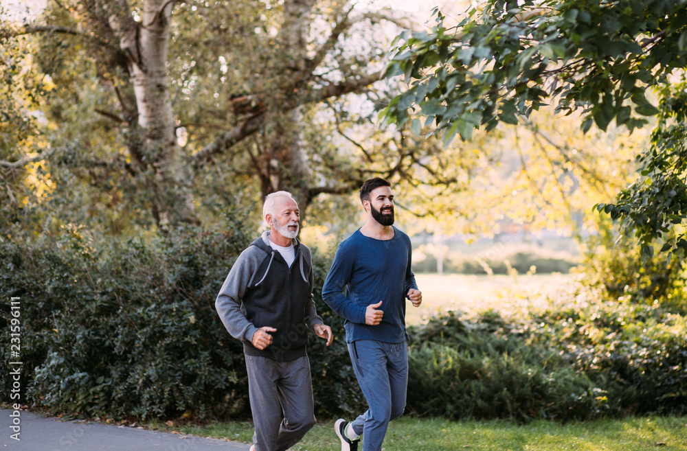 Happy father and son jogging together outdoors in park. Happy father and son jogging together outdoors in park.