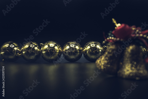 Desaturated golden Christmas balls and bells on black background.