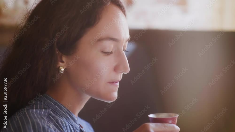 Side view of Woman is drinking tea from chinese red cup