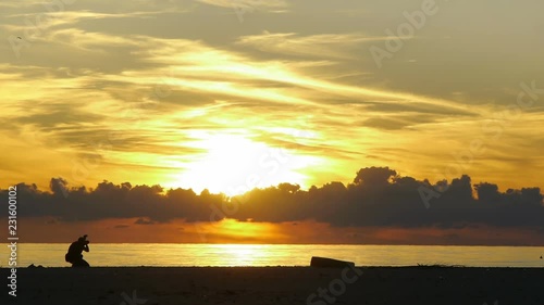 Nature photographer taking picture of sunset on the sea