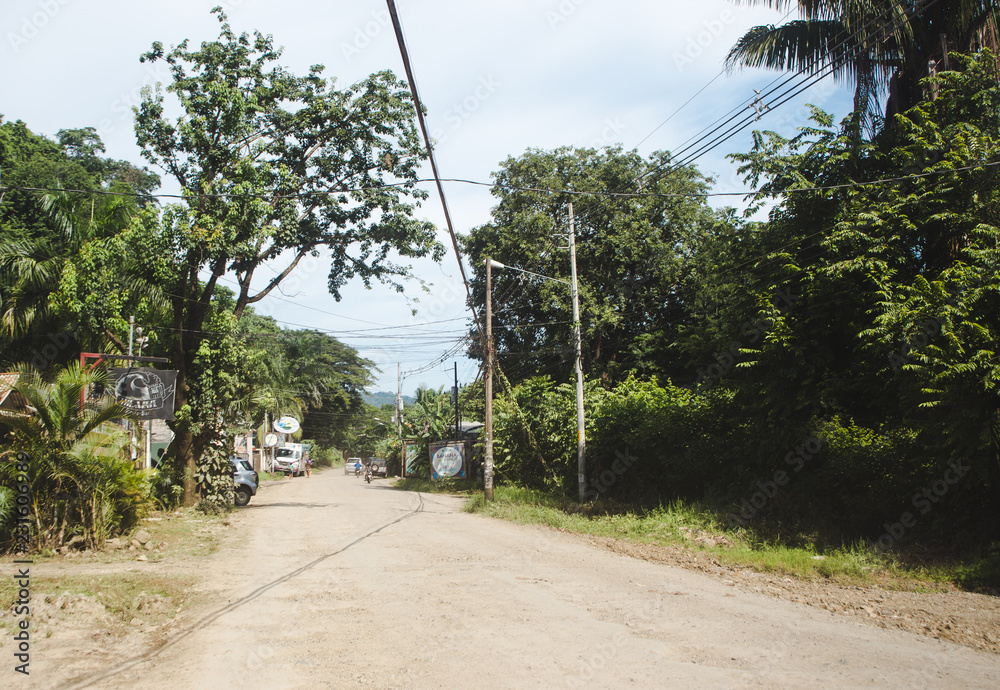 Fototapeta premium Dusty main road through the small town of Santa Teresa, on the pacific coast of the Nicoya peninsula, Costa Rica