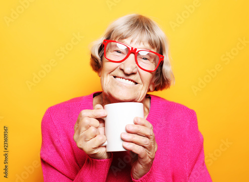 Portrait of old excited lady smiling laughing, holding cup drinking coffee, tea