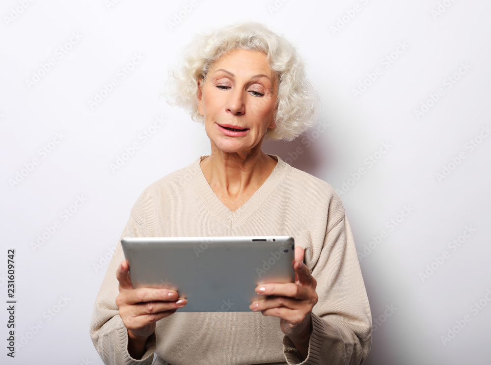 Happy mature woman using a tablet, communicates with children and grandchildren Happy mature woman using a tablet, communicates with children and grandchildren