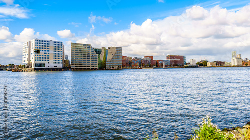 The busy waters of the harbor of Amsterdam in the Netherlands, named Het IJ, surrounded by modern architectural buildings photo