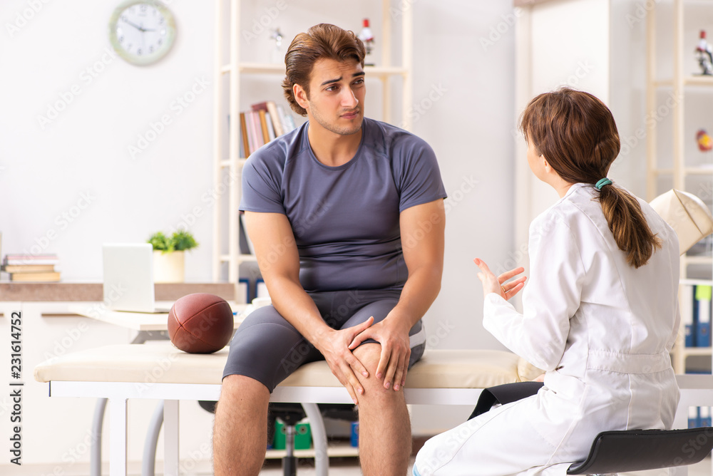 Handsome american footbal player visiting female doctor traumato Handsome american footbal player visiting female doctor traumato