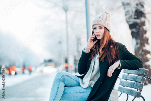 Young woman smiling with smart phone and winter landscape .