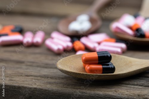 Medication placed in a wooden spoon has a wooden floor background.