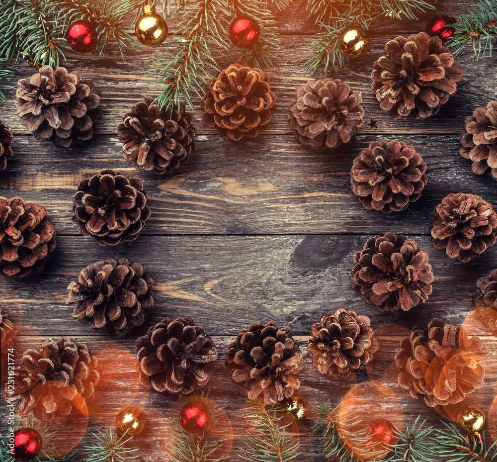 Old wooden Christmas background. Fir branches with baubles and gold stars. Cones in the shape of a circle.  Top view. Space for Xmas congratulation text. Light effect.