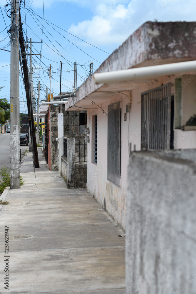 Typical Mexican street sidewalk with traditional small house and moldy concrete surfaces