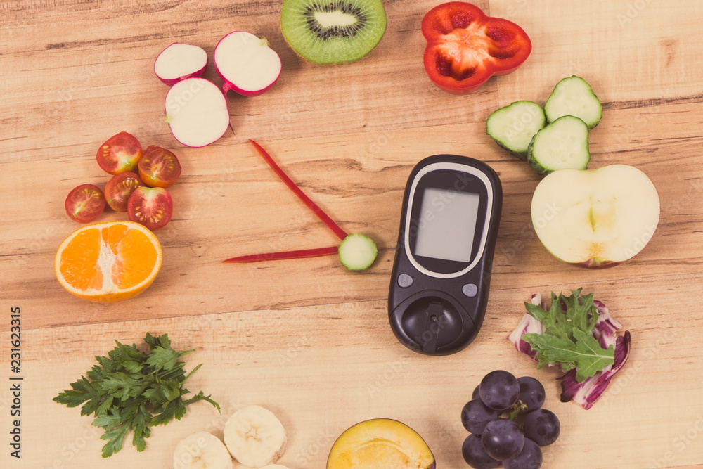 Glucose meter for checking sugar level and fruits with vegetables in shape of clock, healthy food for diabetics concept