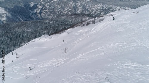 Aerial - Freeride skier going downhill and doing two jumps