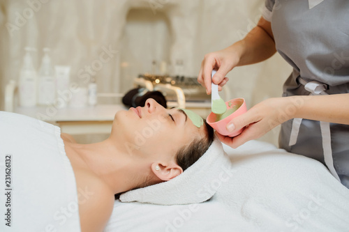 Close up head shot of a Woman having a green mask applied in spa