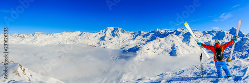 Ski in winter season, mountains and ski touring man on the top in sunny day in France, Alps above the clouds.