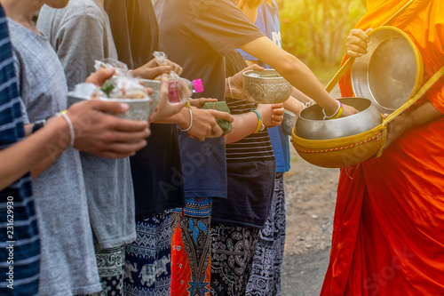 People are making merit by offering food and water into the monk alm bowl in the morning , buddhist tradition. 