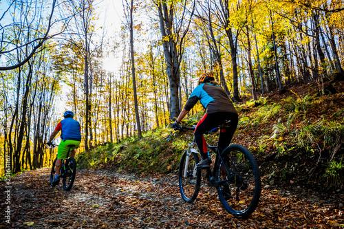 Cycling woman and man at Beskidy mountains autumn forest landscape. Couple riding MTB enduro track. Outdoor sport activity.