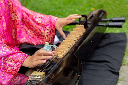 Asian woman is playing Thai wooden string music instruments on the ground. 