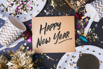 happy new year brush stroke handwriting on golden greeting card with party cup,party blower,tinsel,confetti.Holiday celebrate party time.top view tabletop.