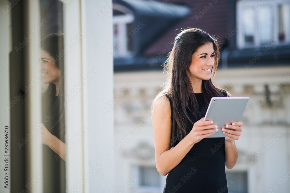 Young businesswoman with tablet standing on a terrace outside an office in city. Young businesswoman with tablet standing on a terrace outside an office in city.