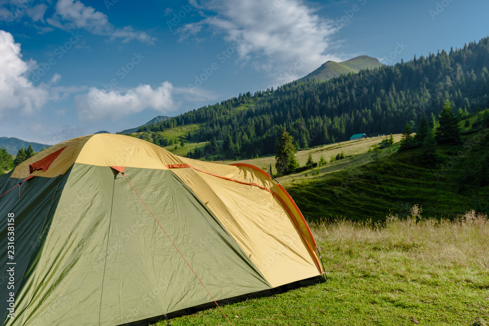 Closeup of tourist tent on grassy hill in mountains