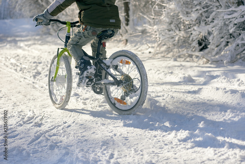 Closeup of young boy with bicycle on snow cover road © Denys Kurbatov