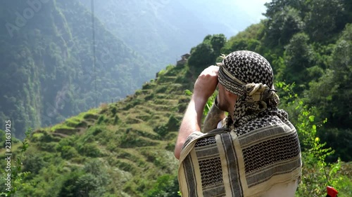 Hiker looking through binoculars on a trekking trail to the Annapurna base camp, the Himalayas, Nepal. photo