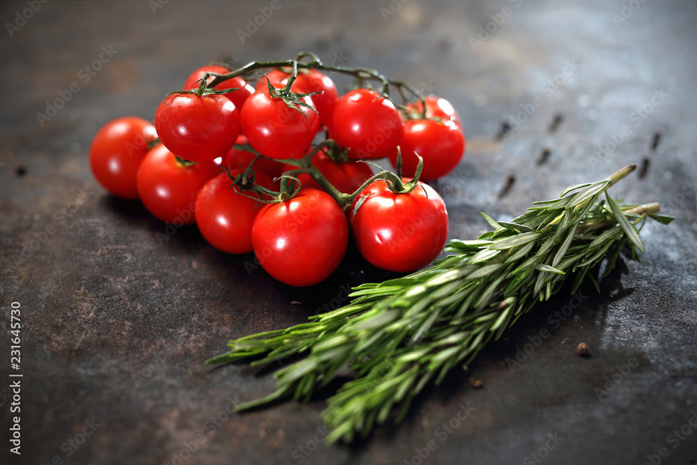 Pomidory i rozmaryn Gałązka pomidorów koktajlowych i aromatycznych ziół rozmarynu na czarnym tle. - obrazy, fototapety, plakaty 