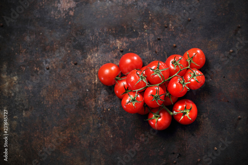Pomidorki. Gałązka dojrzałych czerwonych pomidorków na ciemnym tle.