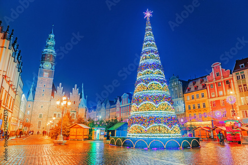 Illuminated Christmas tree at central Square of old city on Christmas Market in Wroclaw, Poland. New Year ambiance, illuminated and ornamented festive city. Night scene. European traditions.
