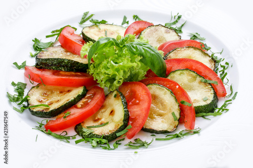 Fried vegetable marrows with greenery and tomatoes.
