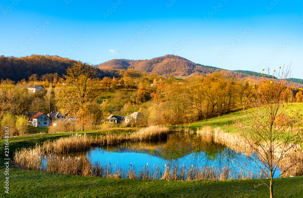 Beautiful autumn landscape with traditional houses and a lake in Sighetu Marmatiei, Maramures region - Romania