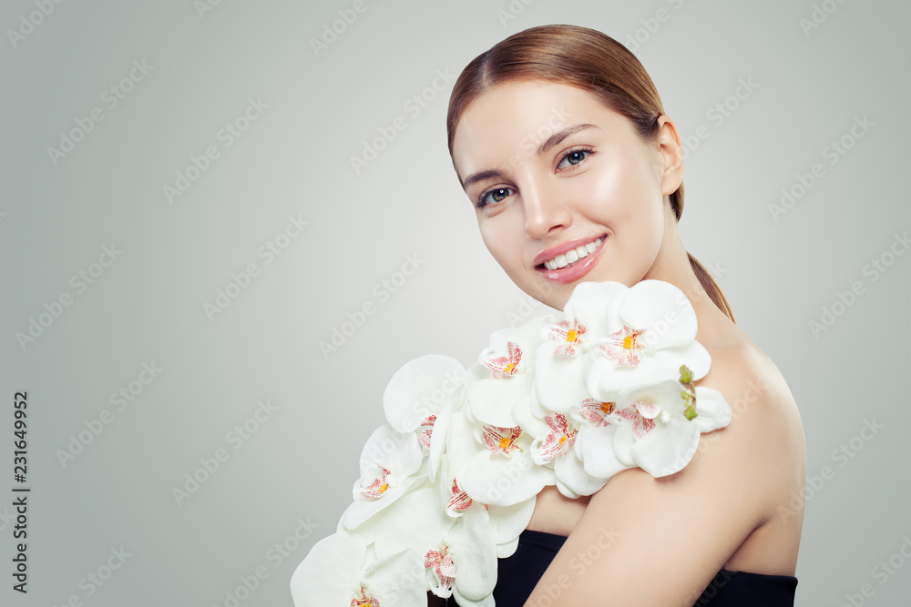 Portrait of happy young woman with healthy skin and white orchid flower
