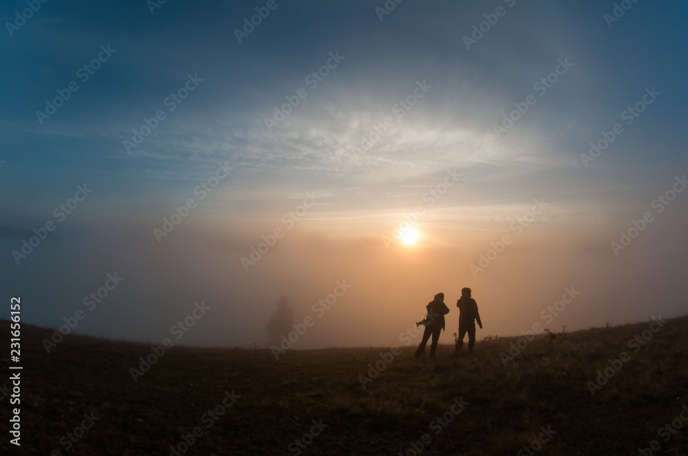 Silhouettes of people on top of mountain at sunrise