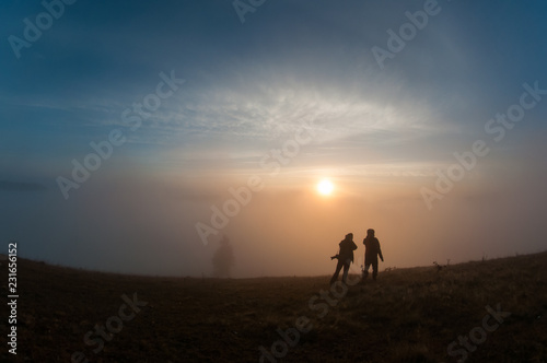 Silhouettes of people on top of mountain at sunrise