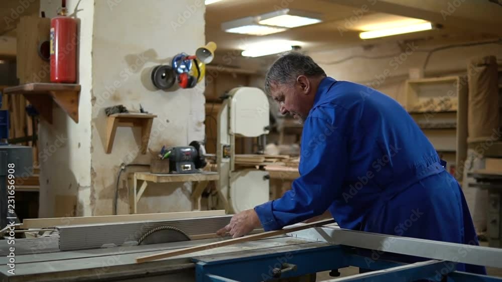 Carpenter at work at his workshop, wood processing on a woodworking machine Carpenter at work at his workshop, wood processing on a woodworking machine