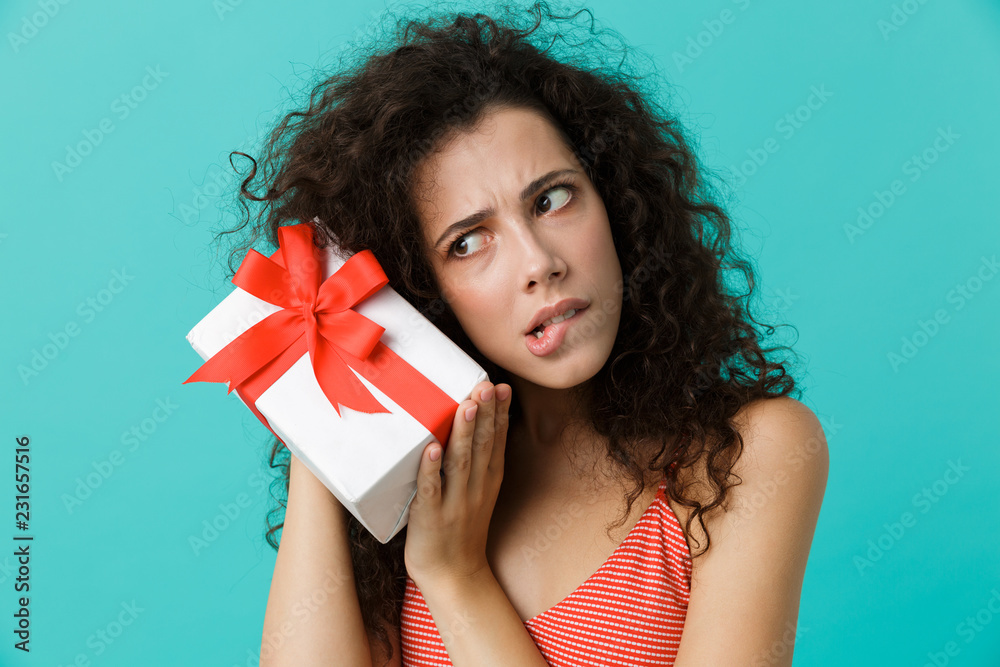 Portrait of excited woman 20s wearing casual clothing holding gift box, isolated over blue background