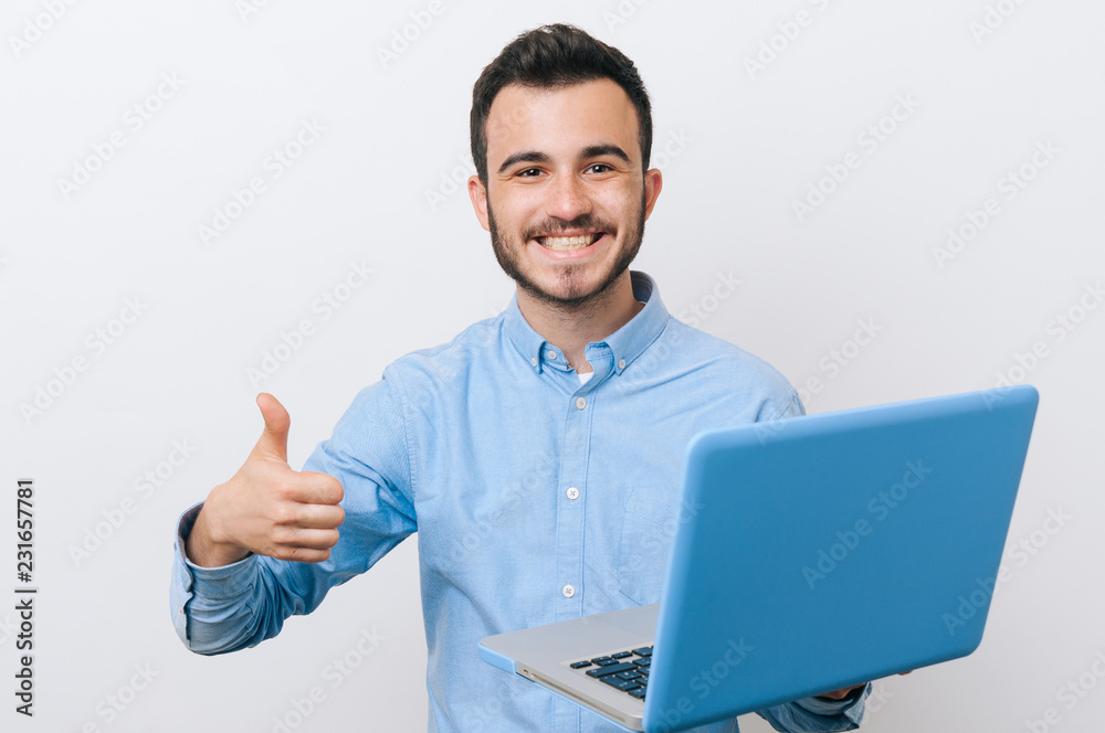 Happy man in casual smiling holding laptop and showing thumbs up gesture over white background Happy man in casual smiling holding laptop and showing thumbs up gesture over white background