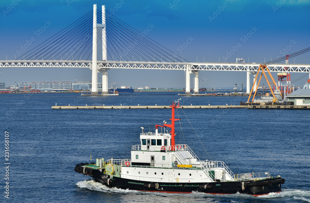 Scenery of a bridge and the tugboat of a blue sky and the port which it was fine in Japanese Yokohama Port