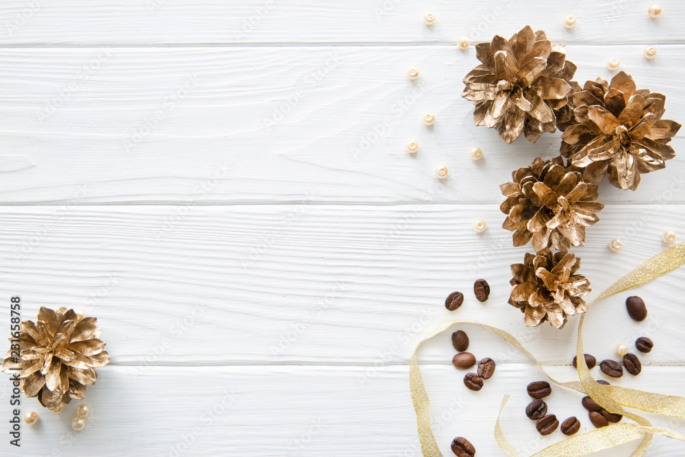 Golden pine cones and golden ribbon on white wooden table background, top view, copy space. Golden pine cones and golden ribbon on white wooden table background, top view, copy space.