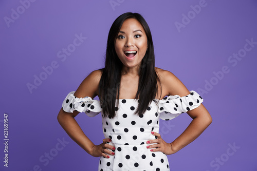 Portrait of a cheerful asian woman in dress standing